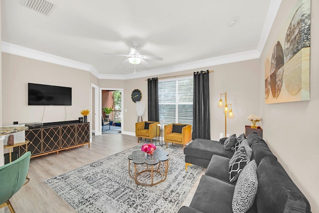 living room with a ceiling fan, baseboards, visible vents, light wood-type flooring, and crown molding