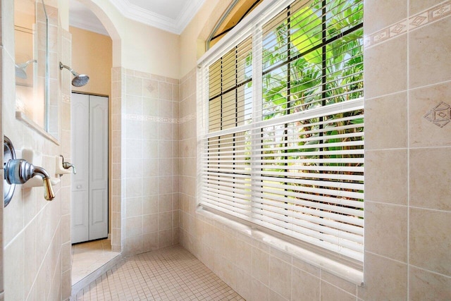 bathroom featuring ornamental molding, tile walls, a tile shower, and tile patterned flooring