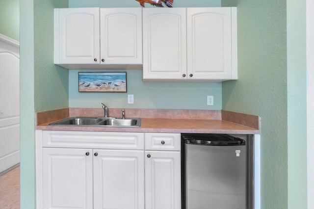 kitchen featuring white cabinetry, stainless steel refrigerator, and sink