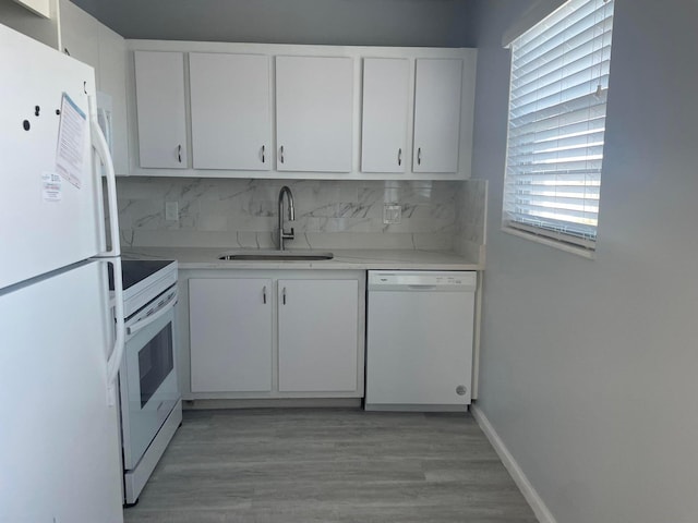 kitchen featuring white appliances, sink, light hardwood / wood-style floors, tasteful backsplash, and white cabinetry