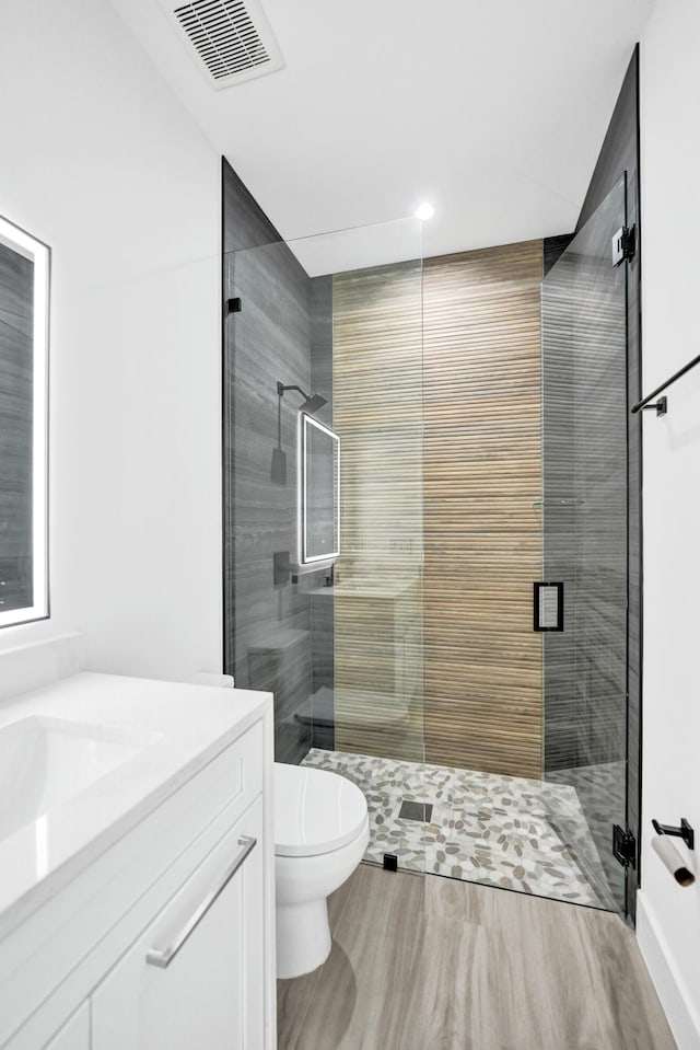 bathroom featuring an enclosed shower, toilet, and vanity