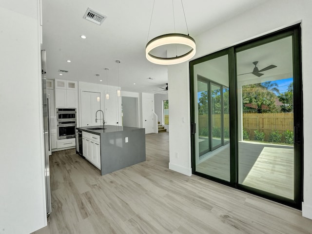 kitchen featuring hanging light fixtures, white cabinets, ceiling fan, and sink