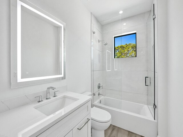 full bathroom featuring toilet, vanity, tiled shower / bath combo, and wood-type flooring