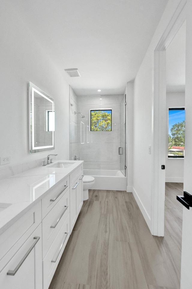 full bathroom featuring tiled shower / bath, toilet, vanity, and hardwood / wood-style floors