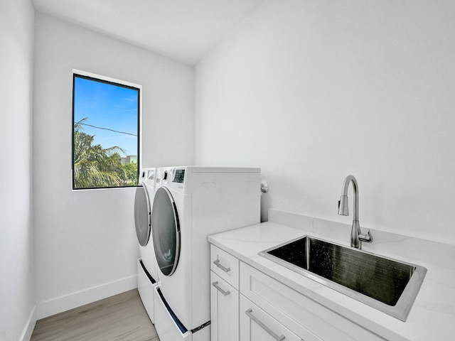 clothes washing area featuring cabinets, washing machine and clothes dryer, and sink