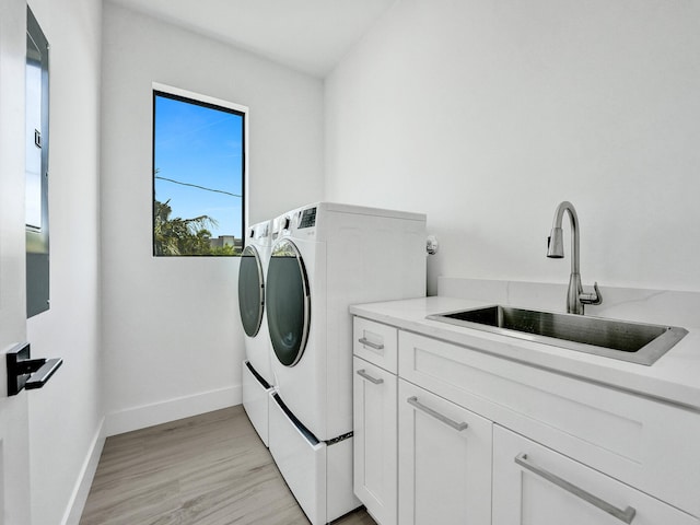 washroom featuring light hardwood / wood-style floors, cabinets, separate washer and dryer, and sink