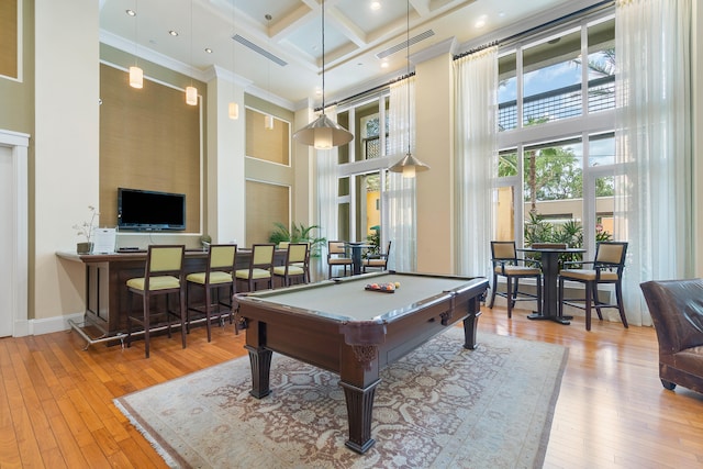 game room with a high ceiling, ornamental molding, coffered ceiling, and light wood-type flooring