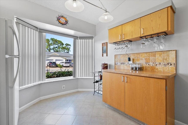 kitchen featuring white fridge, a textured ceiling, light tile floors, and tasteful backsplash