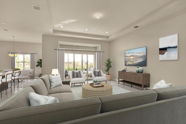 living room with an inviting chandelier, a raised ceiling, and a healthy amount of sunlight