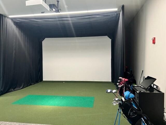 game room with carpet and golf simulator