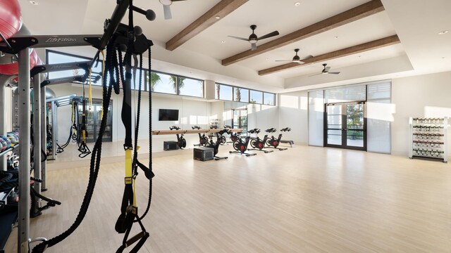 gym with wood-type flooring, a raised ceiling, and ceiling fan