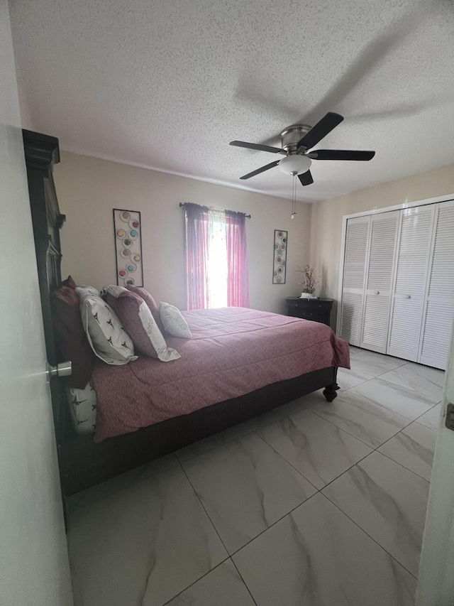 bedroom featuring a closet, a textured ceiling, light tile flooring, and ceiling fan