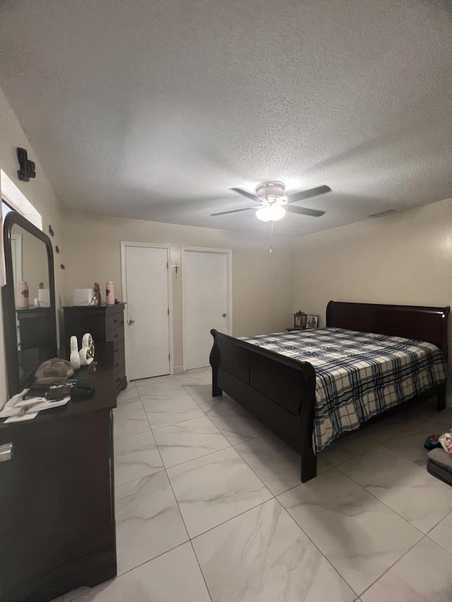 tiled bedroom featuring a textured ceiling and ceiling fan