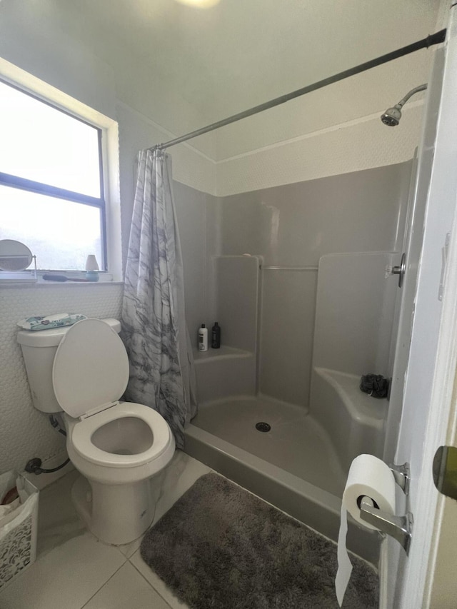 bathroom with toilet, tile floors, and a shower with shower curtain