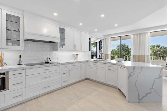 kitchen featuring white cabinets, oven, black electric stovetop, and backsplash