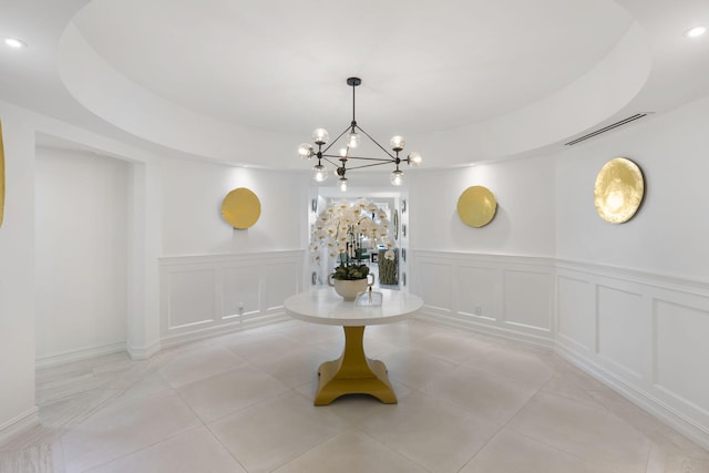 tiled empty room featuring a chandelier and a tray ceiling