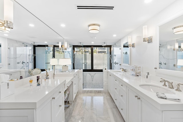 bathroom featuring tile flooring, a shower with door, large vanity, and double sink