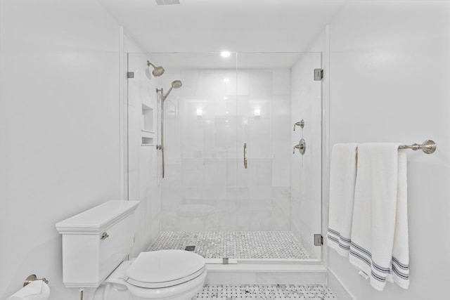 bathroom featuring toilet, a shower with door, and tile flooring