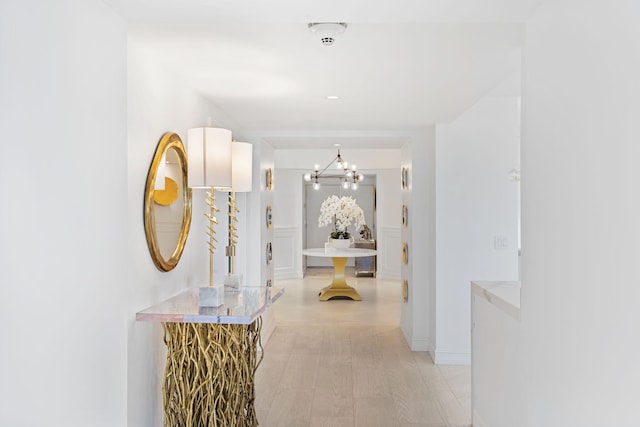 hallway featuring an inviting chandelier and light hardwood / wood-style floors