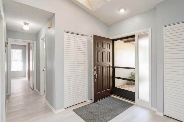 foyer entrance featuring a textured ceiling and light wood-type flooring