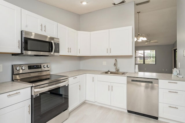 kitchen featuring an inviting chandelier, appliances with stainless steel finishes, white cabinets, and sink