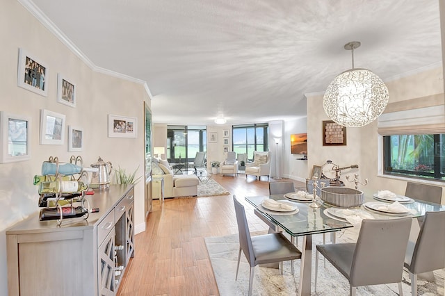 dining area featuring crown molding, light wood-type flooring, and an inviting chandelier