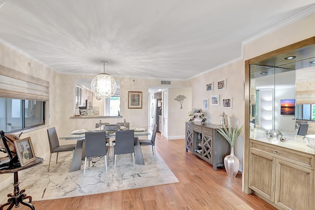 dining space featuring an inviting chandelier, ornamental molding, and light hardwood / wood-style floors