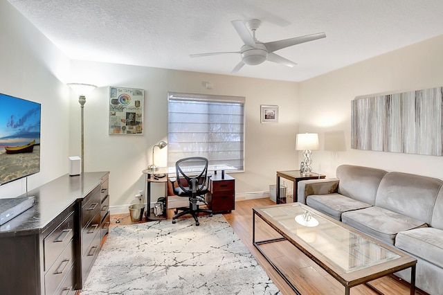 living room featuring a textured ceiling, ceiling fan, and light wood-type flooring