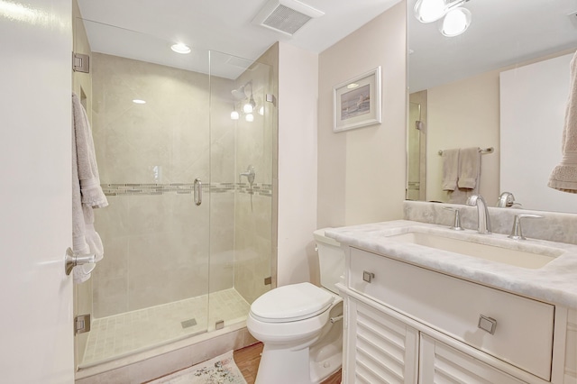 bathroom with hardwood / wood-style flooring, walk in shower, vanity, and toilet