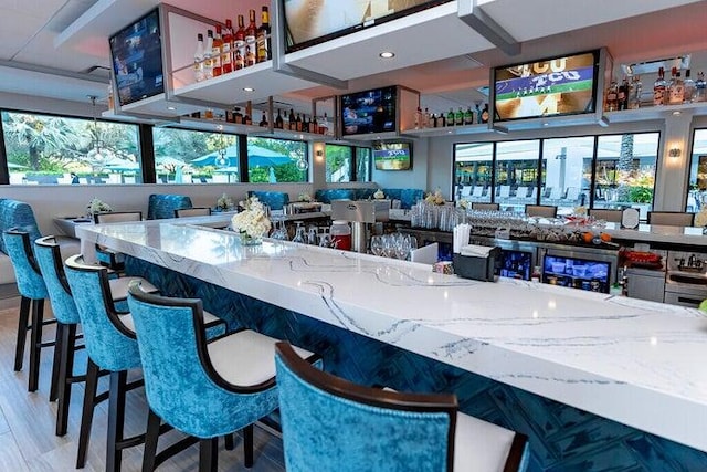 bar featuring hardwood / wood-style flooring, light stone countertops, and a wealth of natural light