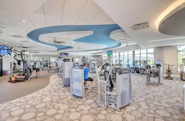 gym with floor to ceiling windows, light colored carpet, a drop ceiling, and ceiling fan