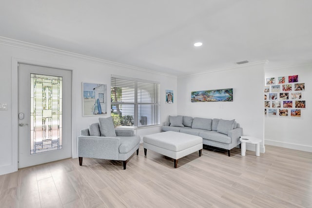 living room featuring a wealth of natural light, ornamental molding, and light hardwood / wood-style flooring