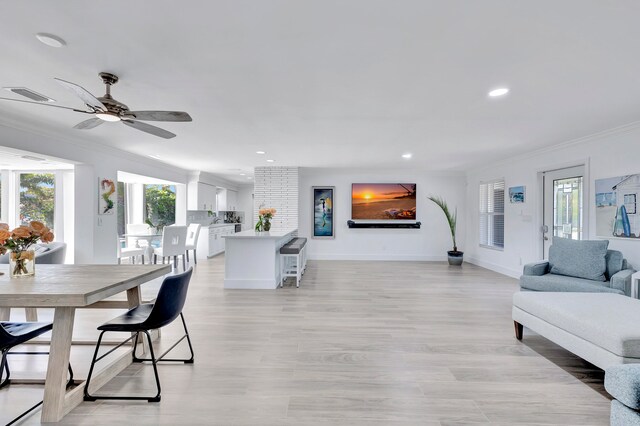 dining space with light hardwood / wood-style floors, ornamental molding, and ceiling fan