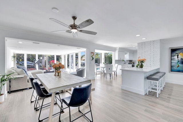 dining space featuring ceiling fan, light hardwood / wood-style floors, brick wall, and ornamental molding