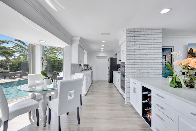 dining area featuring light hardwood / wood-style floors, sink, brick wall, and crown molding