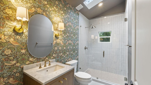 bathroom featuring lofted ceiling with skylight, vanity, a shower with door, and toilet