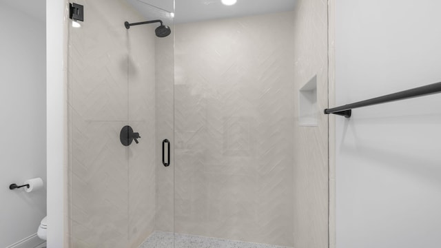 bathroom featuring a shower with shower door and toilet