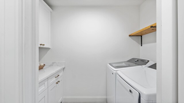 clothes washing area with washer and clothes dryer and cabinets