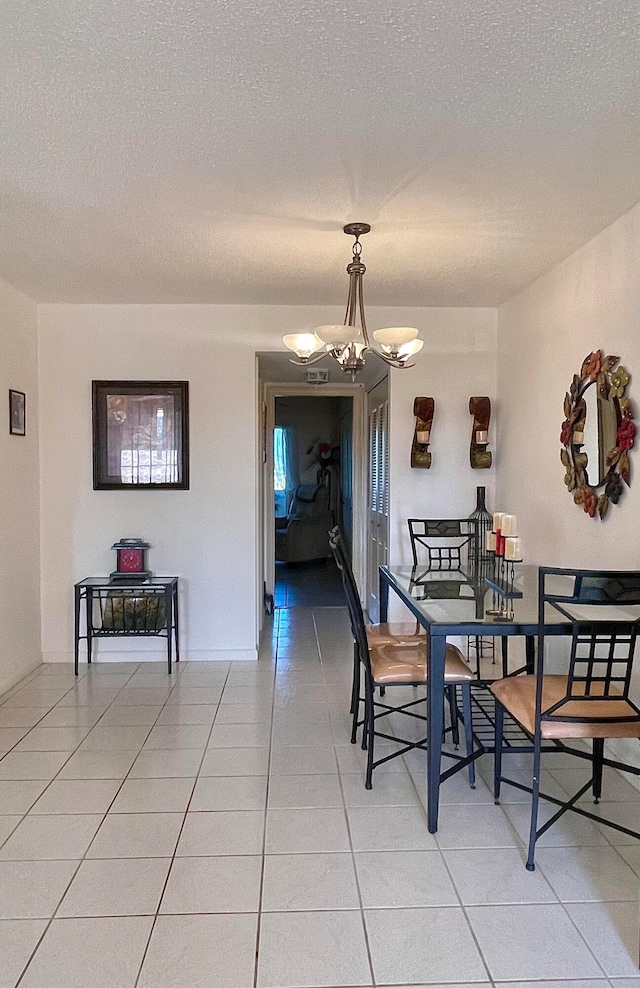 dining area featuring an inviting chandelier, a textured ceiling, and light tile flooring