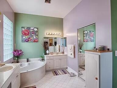 bathroom with tile flooring, a washtub, and dual vanity