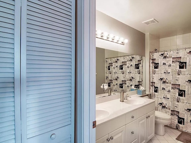 bathroom with large vanity, tile flooring, dual sinks, and toilet