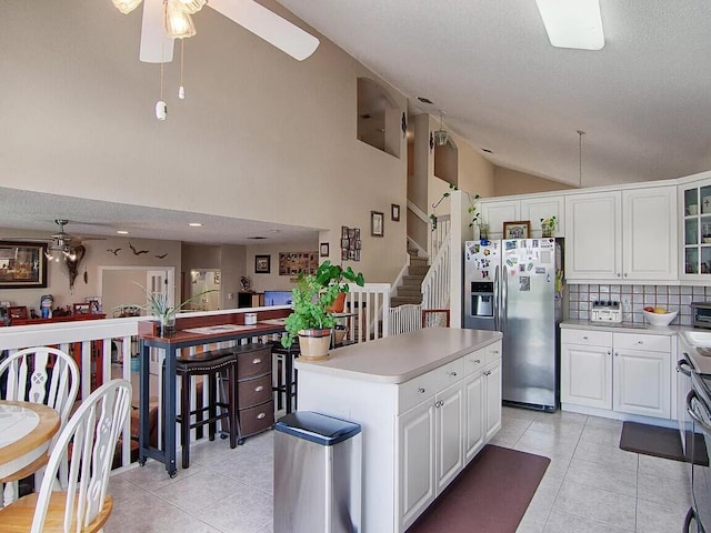 kitchen featuring a kitchen island, white cabinetry, stainless steel refrigerator with ice dispenser, and ceiling fan