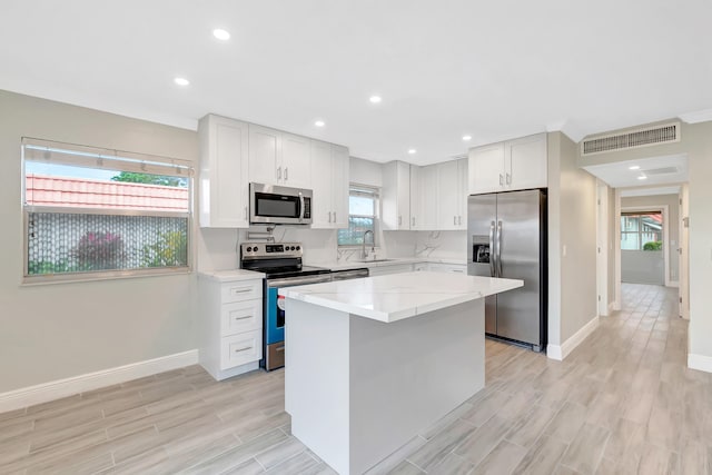 kitchen with white cabinets, a center island, a wealth of natural light, and stainless steel appliances