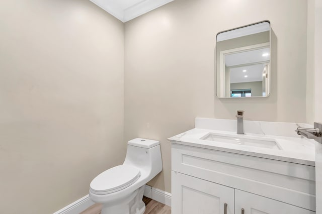 bathroom with vanity, wood-type flooring, toilet, and ornamental molding