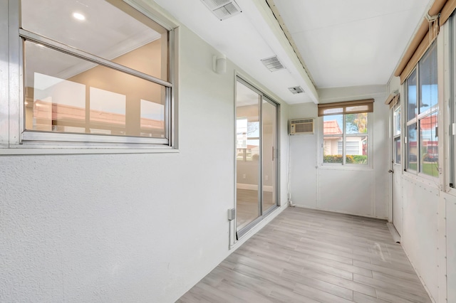 corridor with a wall mounted air conditioner and light hardwood / wood-style flooring