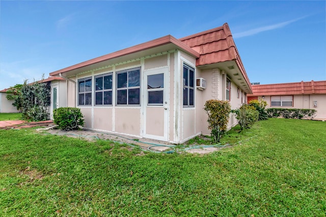 view of home's exterior featuring an AC wall unit and a lawn