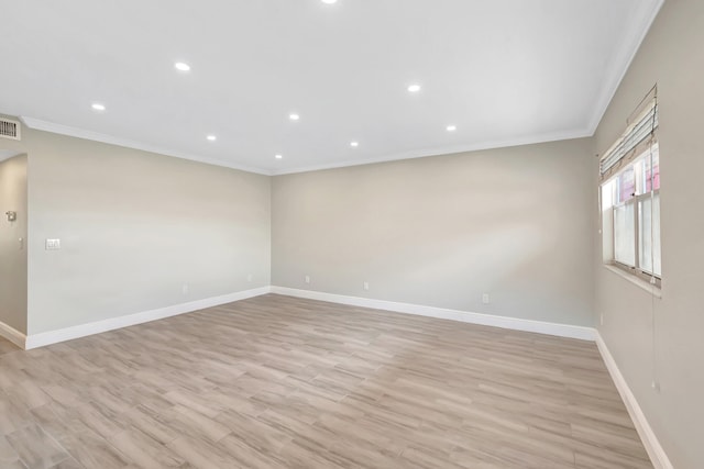 spare room with ornamental molding and light wood-type flooring