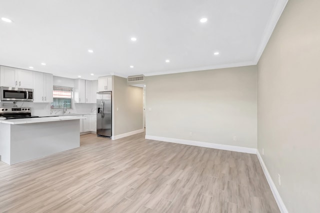 kitchen with stainless steel appliances, white cabinets, and light hardwood / wood-style flooring