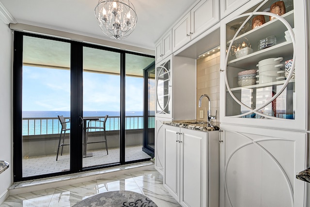 laundry room with cabinets, a water view, a chandelier, and sink