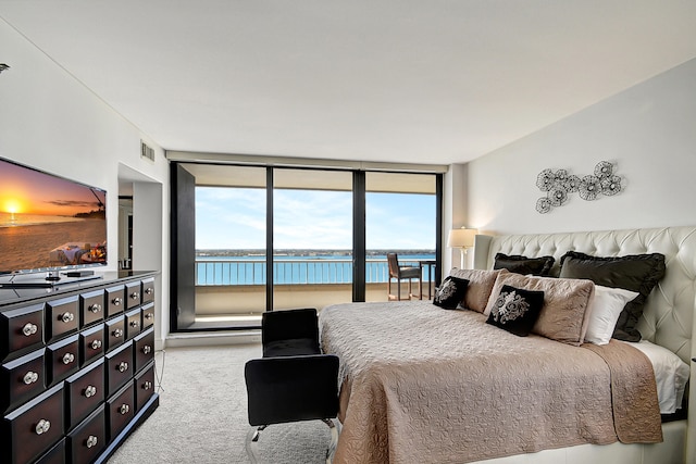 carpeted bedroom with access to exterior, a water view, and expansive windows